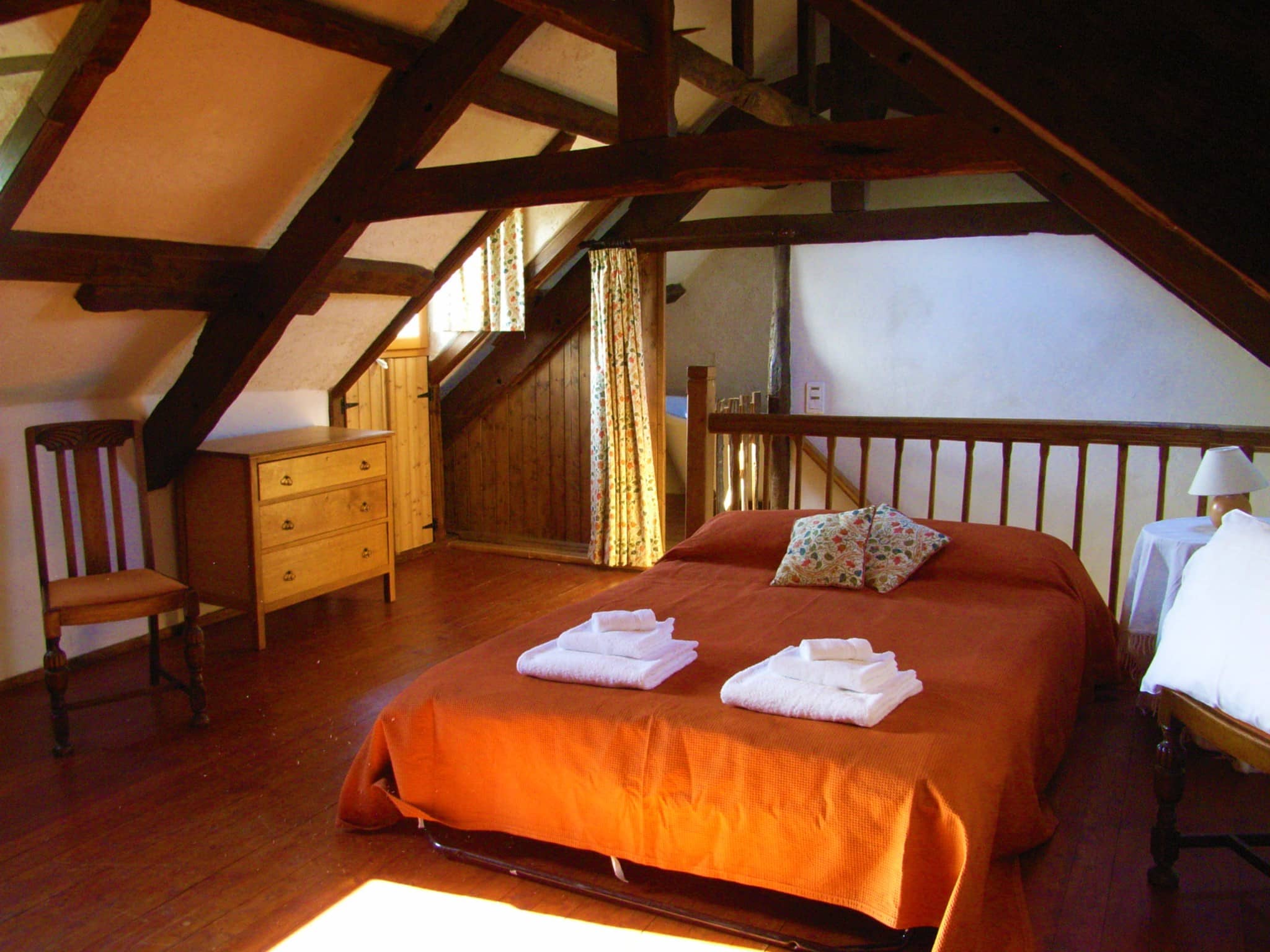 Spacious and comfortable bedroom of La Julerie cottage in Brittany, France, with a king-size bed, elegant rustic decor, a stone fireplace, and a panoramic view of the surrounding countryside. Perfect for a peaceful night's sleep after a day of sightseeing in the Brittany region.